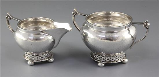 A George V planished silver Arts & Crafts sugar bowl and cream jug, by Albert Edward Jones, jug height 82mm, weight 10.3oz/321grms.